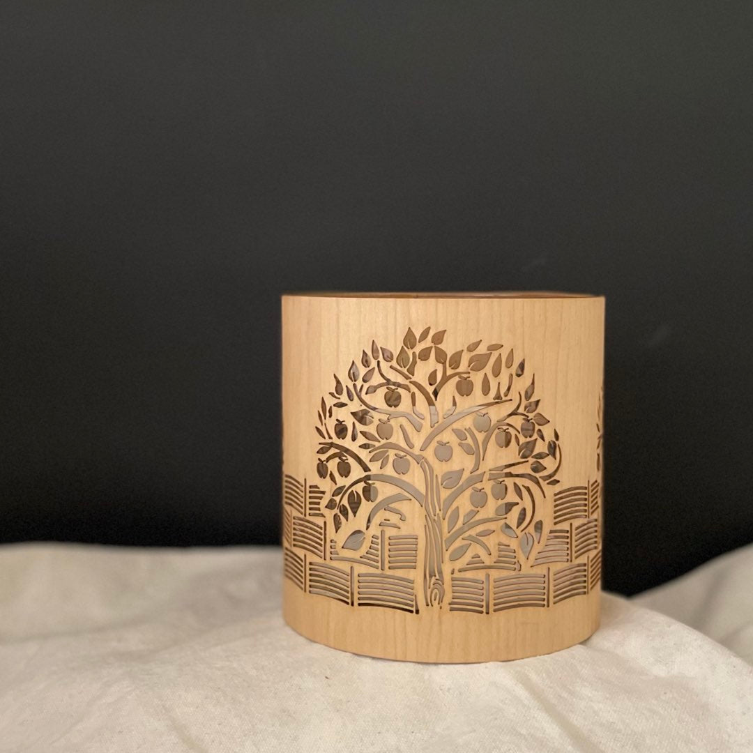 A candle holder or lantern with an apple  orchard design iinspired by kelmscott manor unlit but made from maple wood