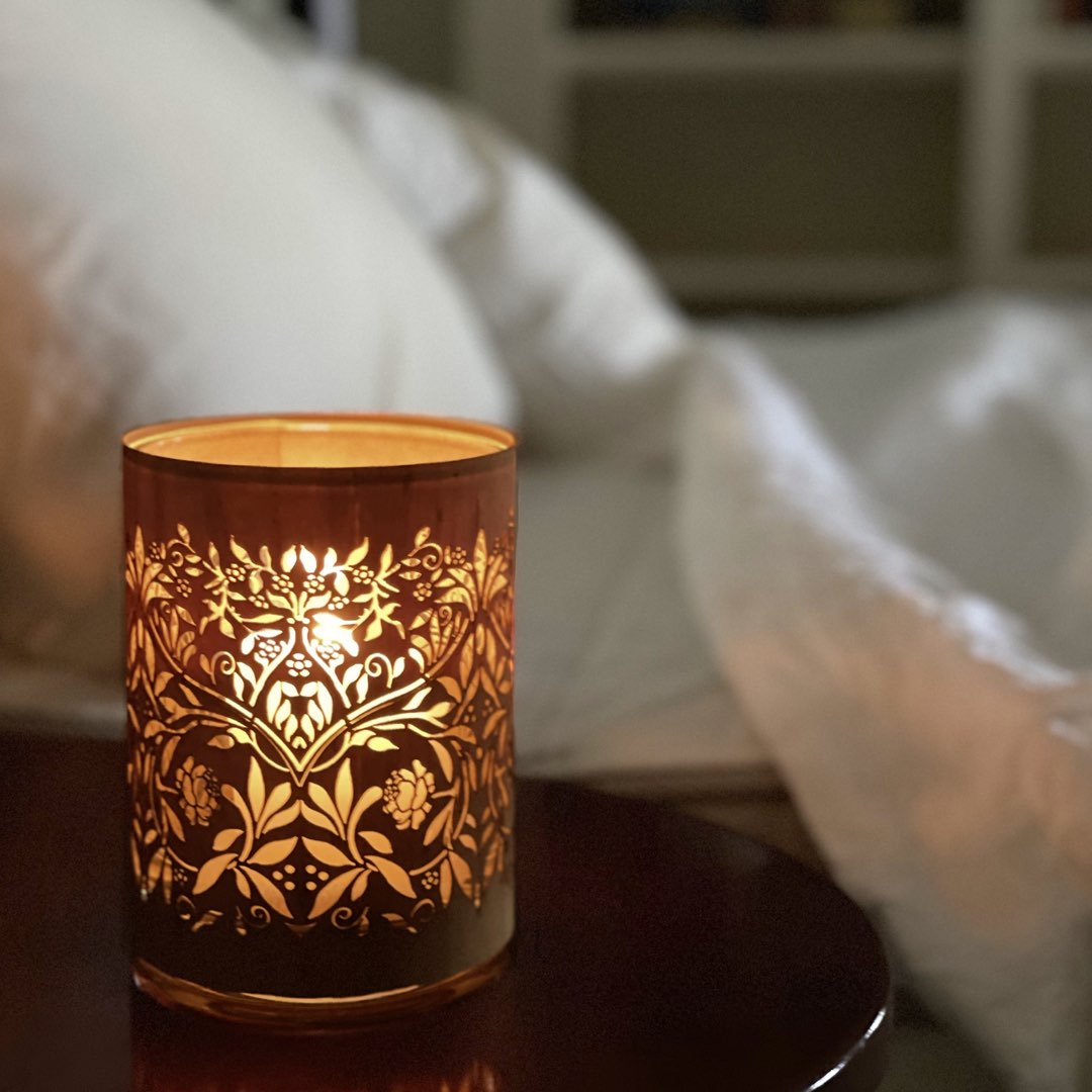 the strawberry thief candle lantern inspired by william morris. on a bedside table