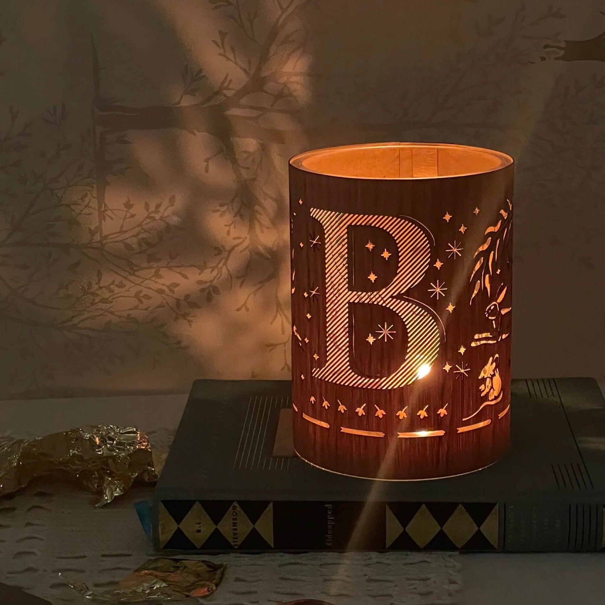 A wood and glass lantern monogrammed with the letter B