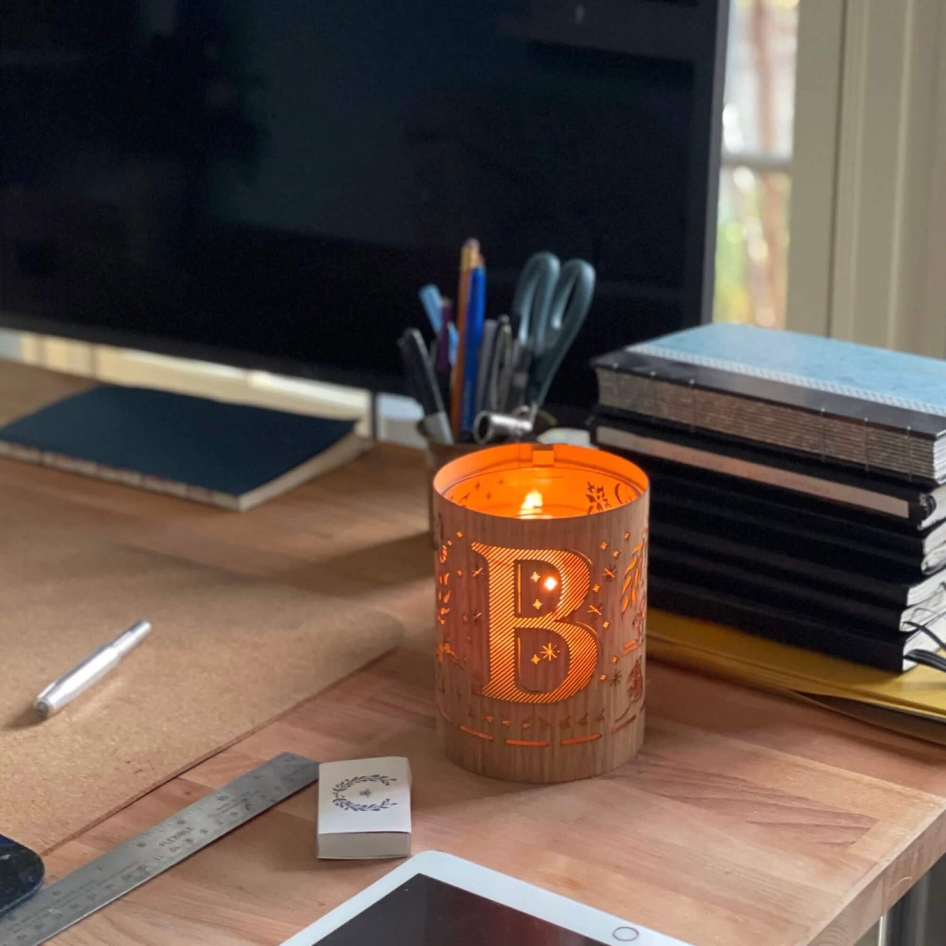 A wood and glass lantern monogrammed with the letter B
