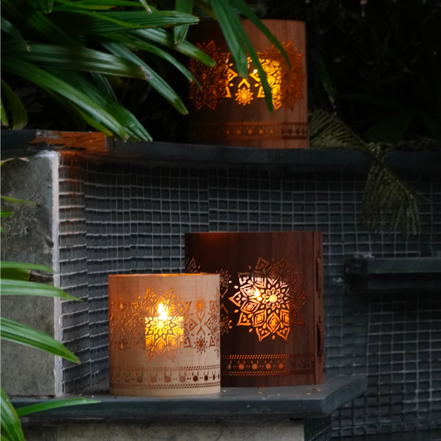 medium maple mandala lantern with a large walnut mandala lantern and a large maple mandala lantern on the ledge of a pool in the garden of a home in Key West Florida Edit alt text