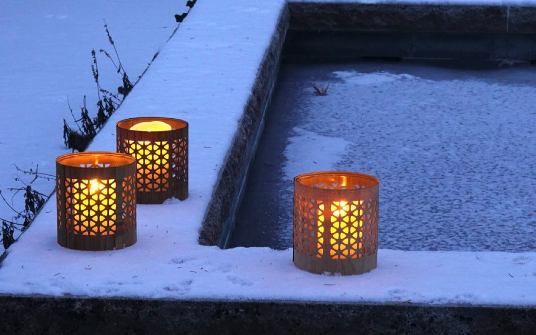 three mid-century modern style lanterns after a snow fall in the evening light