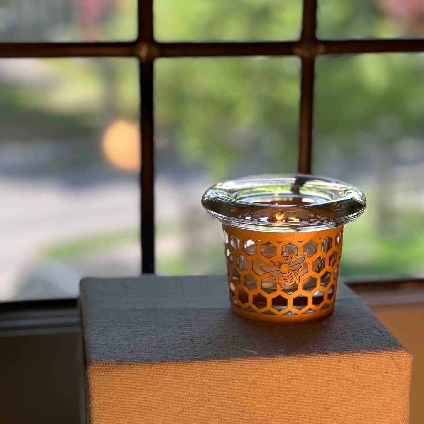 a tea light holder with a honeybee design handmade in maple and glass