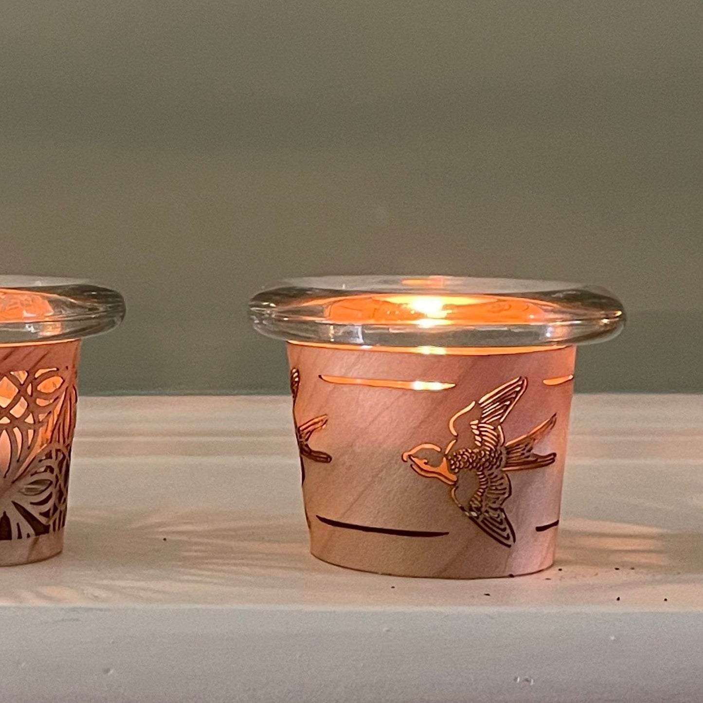 a tea light holder with a bird design handmade in maple and glass