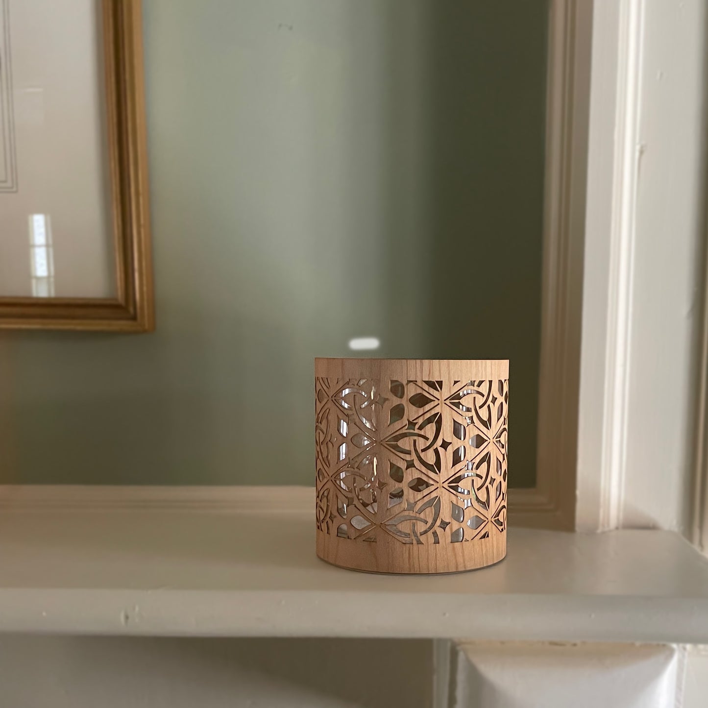 Decorative wooden lantern on a shelf with a mirror in the background. The wood is maple, it is not lit and the light is from a window on the right off the image