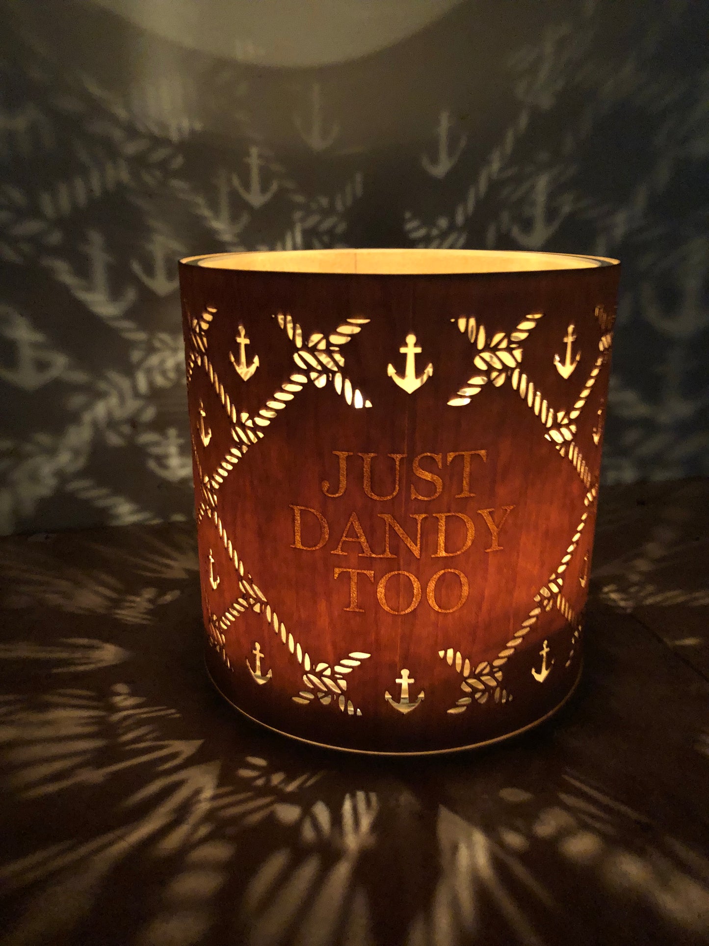 A wooden cover for a Luci Light customized with with 'Just Dandy Too' text and decorative patterns on a dark background