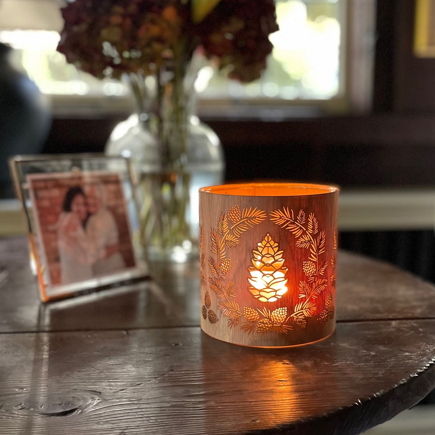 a glass lantern candle holder wrapped in oak veneer with laser cut pinecone design