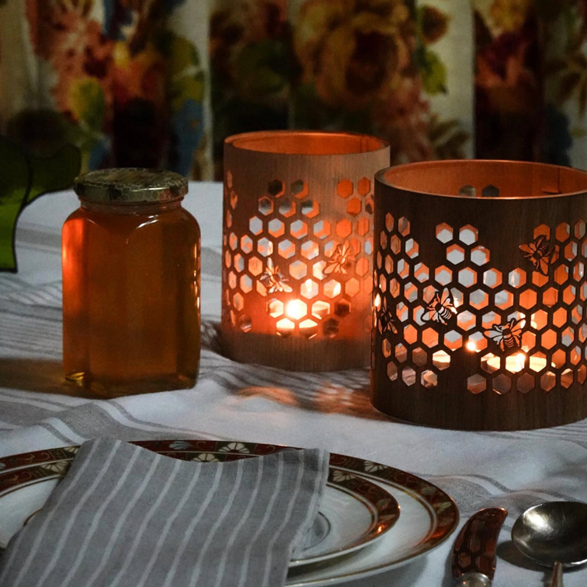 small maple honeybee lantern beside a medium black walnut lantern on the table beside a jar of honey