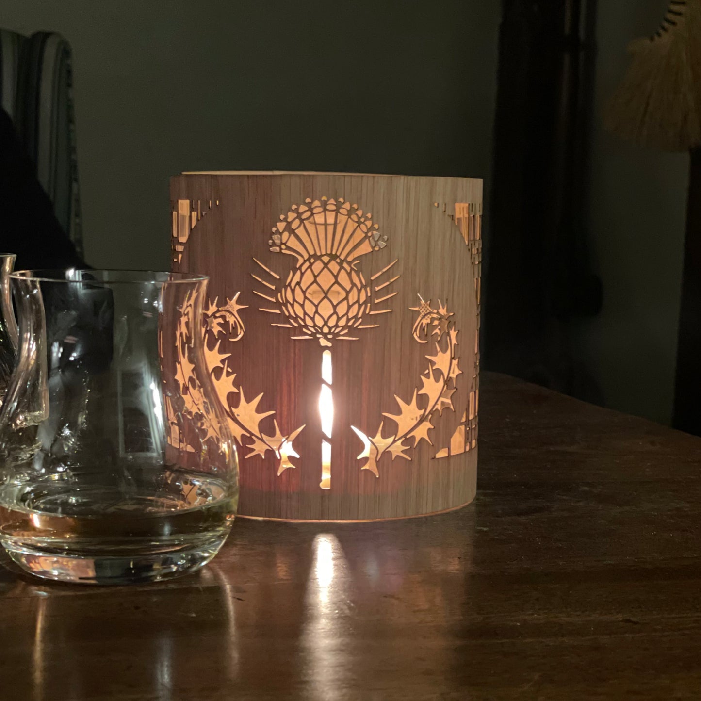 close up of a thistle lantern beside a glass of scotch for Robbie Burns night