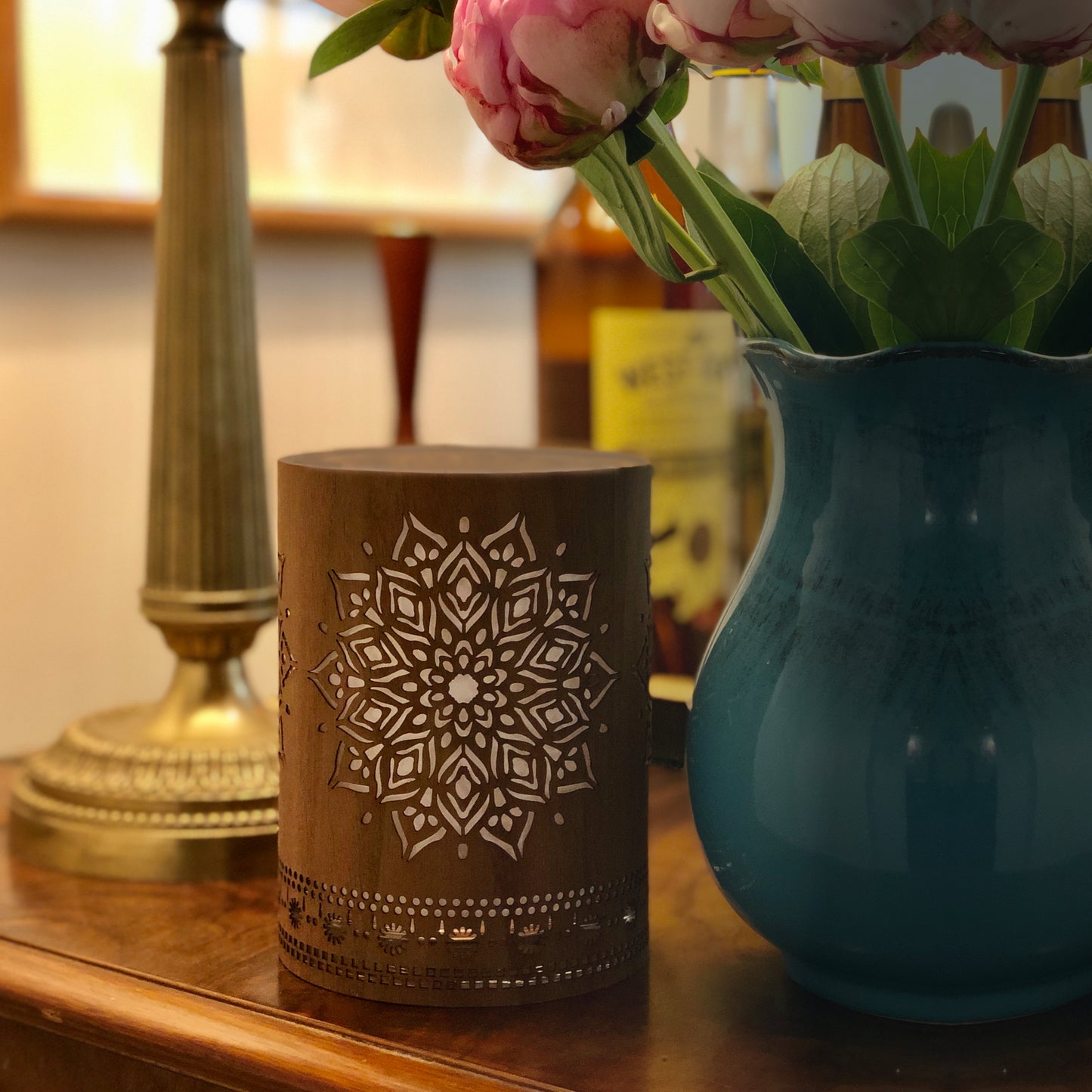 small walnut mandala lantern on a table beside a blue jug