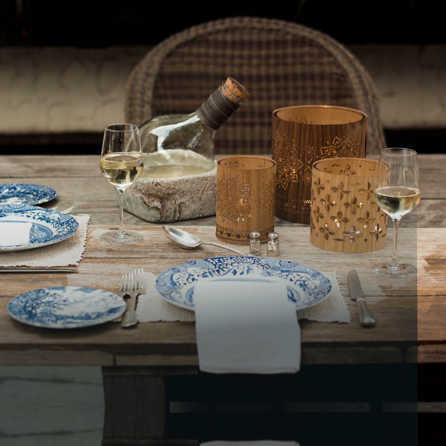 small oak mandala lantern with a large walnut mandala lantern on a wood table outside on the patio - blue Italian dishes