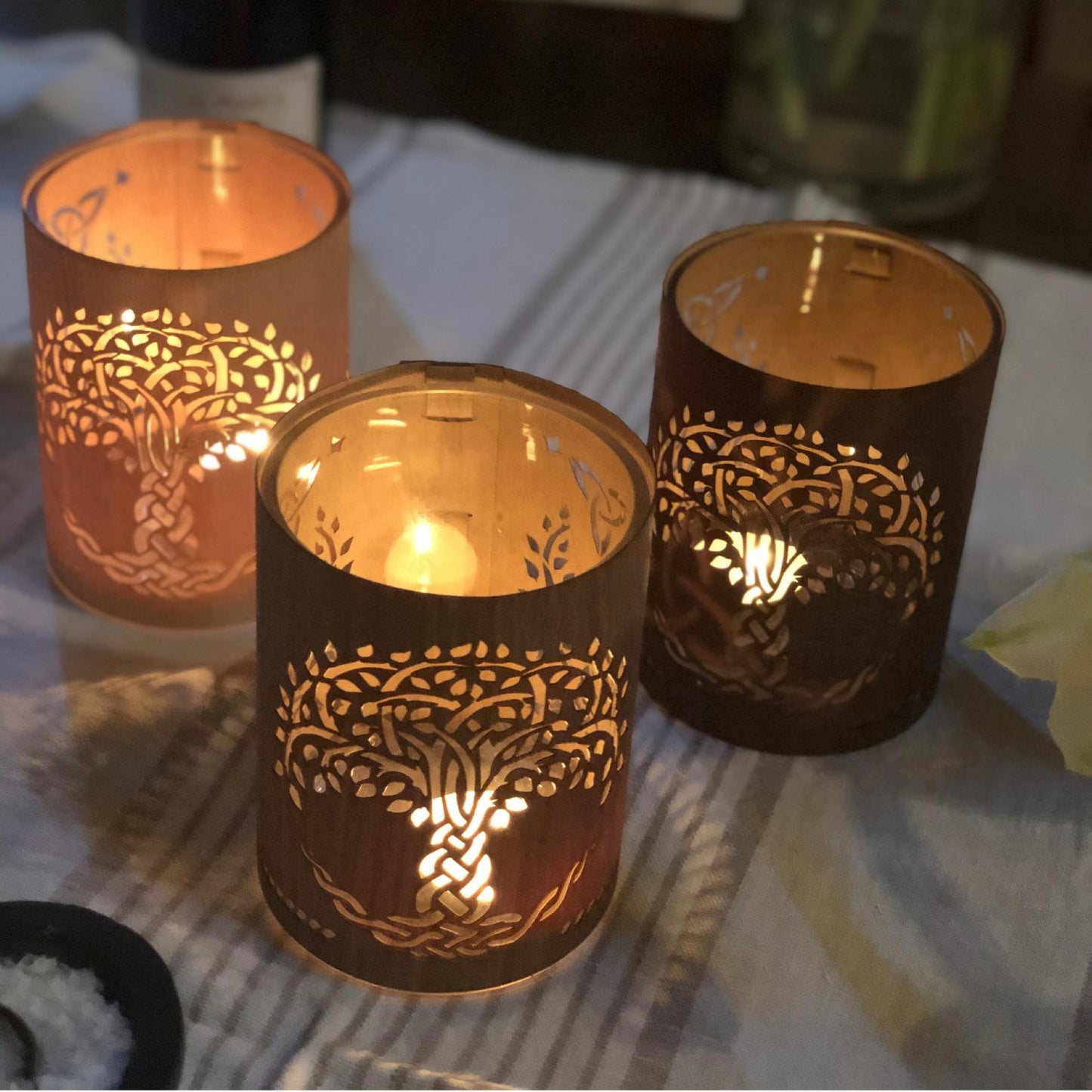 three small tree of life lanterns lit on the dinner table maple, white oak, black walnut