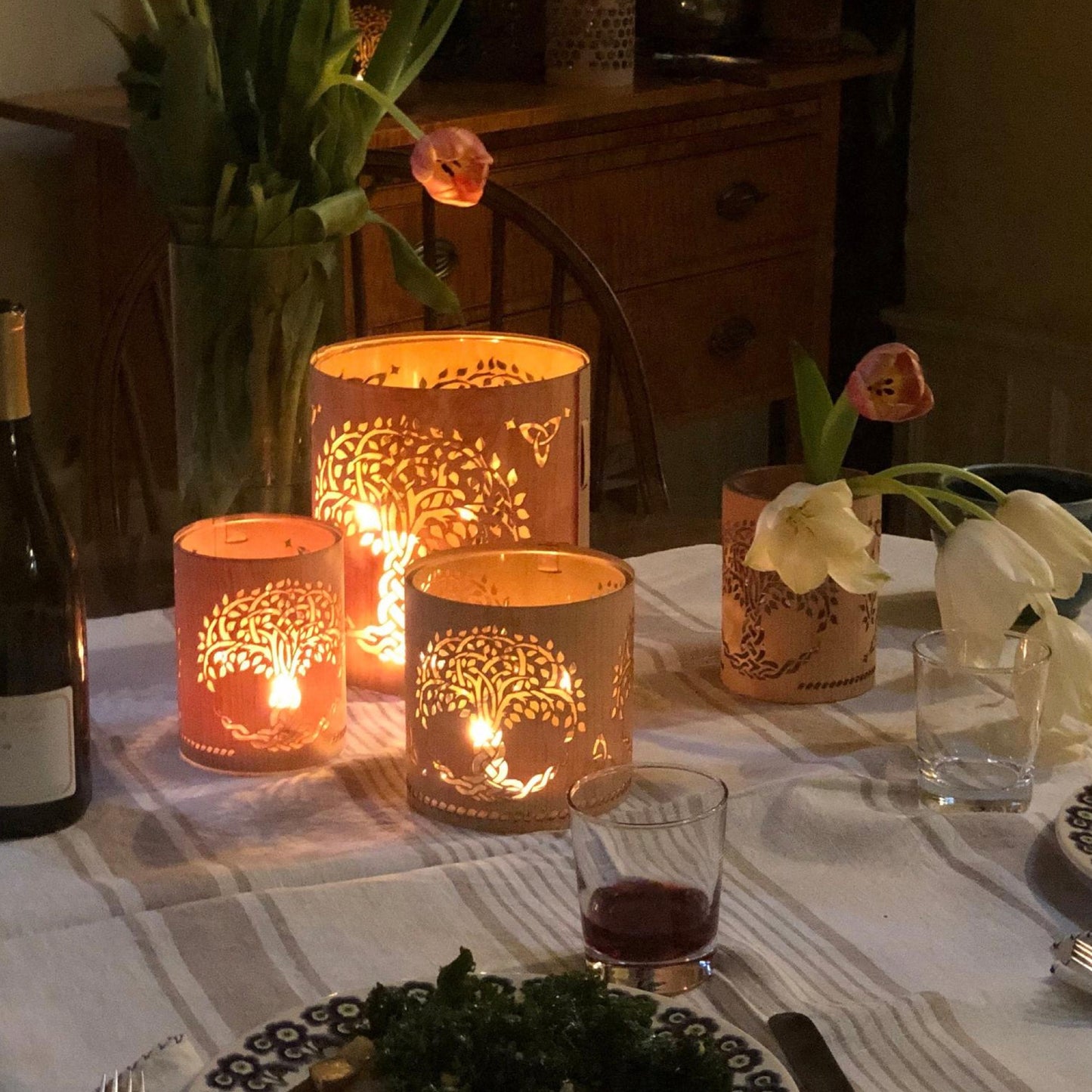 three tree of life lanterns in all three sizes, in maple on the dinner table