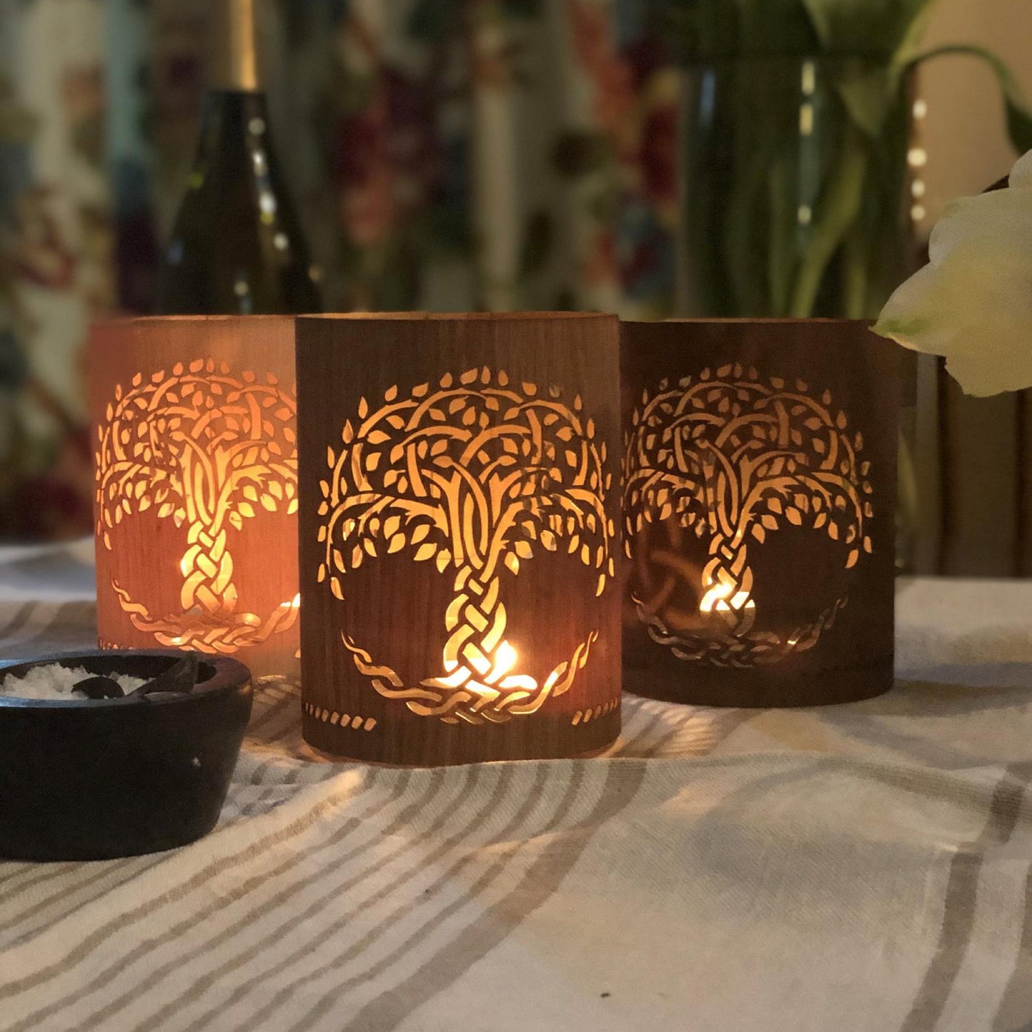 three small tree of life lanterns lit on the dinner table maple, white oak, black walnut