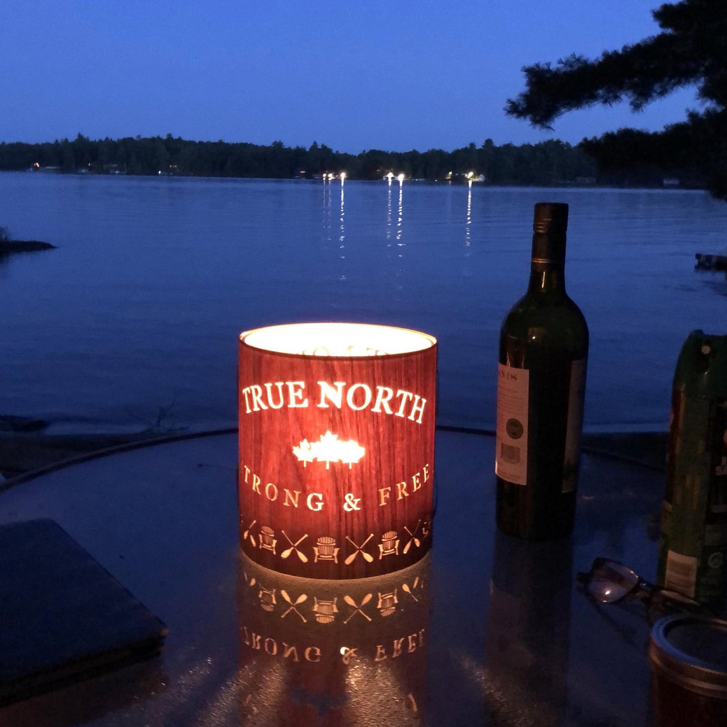 a true north lantern on a glass table over looking lake Muskoka and the midnight blue sky